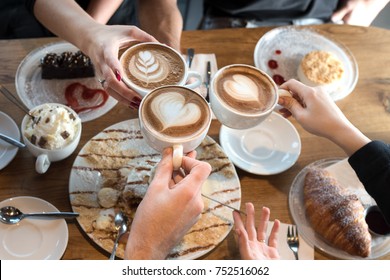 Friends with desserts and coffee, close up.Happy couple sitting around the table. Hands holding cups, happy festive moment, luxury celebration concept.   - Powered by Shutterstock