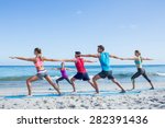 Friends doing yoga together with their teacher at the beach