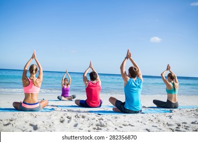 Friends Doing Yoga Together With Their Teacher At The Beach