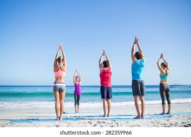 Friends Doing Yoga Together With Their Teacher At The Beach