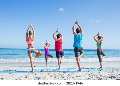 Friends Doing Yoga Together With Their Teacher At The Beach