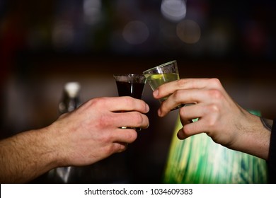 Friends Drink Shot Or Liqueur And Cheers. Party And Celebration Concept. Male Hands Cheer With Alcohol On Blurred Bar Background. Male Hands Cheers With Glasses Of Shot Or Liquor.