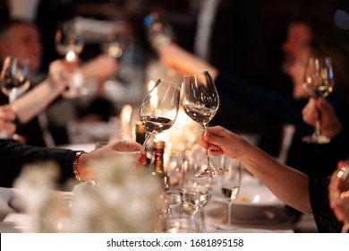 Friends drink wine. Couple toasting wineglasses in a luxury restaurant. Focus on the wineglass. 
Wine brunch.