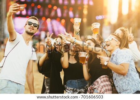 Friends drinking beer and having fun at music festival 