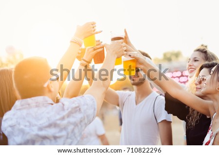 Friends drinking beer and having fun at music festival. Cheers