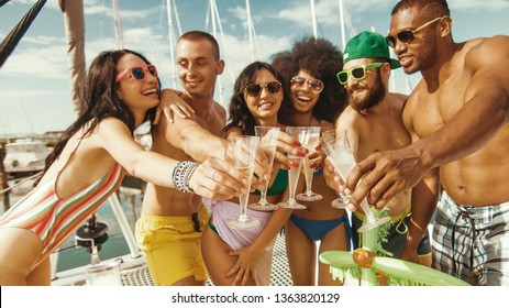 friends drinking champagne on a boat party. group of young rich people on  yacht in swimwear, toasting with sparkling wine celebrating smiling having fun.  
