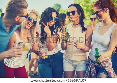 Friends drinking, cheering, dancing and partying outdoors