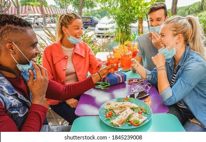 Friends Drinking Cocktail And Eating Snack Tapas In A Restaurant Bar Outside In Summer Days With Face Mask On To Be Protected From Coronavirus - Happy People Cheering With Spritz And Having Fun 