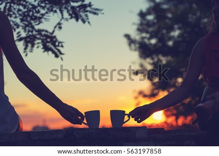 Friends drinking coffee in sunset / sunrise. Shallow depth of field.