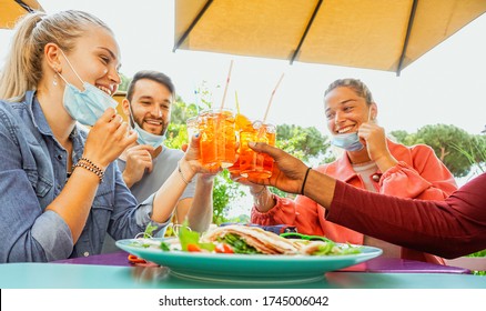 Friends Drinking Coktail And Eating Snack Tapas In A Restaurant Bar Outside In Summer Days With Face Mask On To Be Protected From Coronavirus - Happy People Cheering With Spritz And Having Fun 