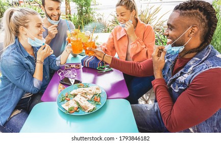 Friends Drinking Coktail And Eating Snack Tapas In A Restaurant Bar Outside In Summer Days With Face Mask On To Be Protected From Coronavirus - Happy People Cheering With Spritz And Having Fun