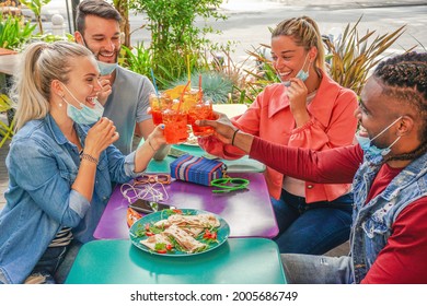 Friends Drinking Coktail And Eating Snack Tapas In A Restaurant Bar Outside In Summer Days With Face Mask On To Be Protected From Coronavirus - Happy People Cheering With Spritz And Having Fun