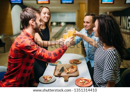 Friends drinks and eats pizza in bowling club