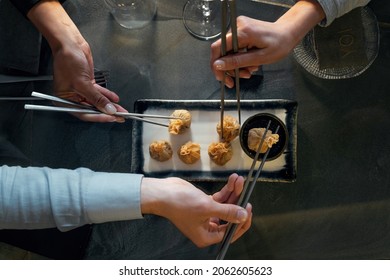 Friends Eating Dim Sum At Fusion Bar Restaurant. Flat Top Image Focusing On The Hand With Metal Chopstick Taking The Food.