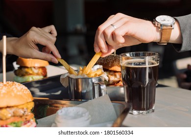 Friends Eating French Fries, Burgers And Drink Cold Dark Beer. 