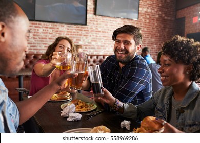 Friends Eating Out In Sports Bar With Screens In Background