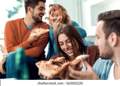 Friends eating pizza.They are having party at home, eating pizza and having fun.
