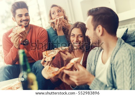 Friends eating pizza.They are having party at home, eating pizza and having fun.