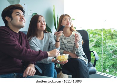 Friends eating potato chips while watching tv together - Powered by Shutterstock