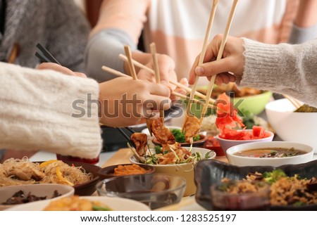 Friends eating tasty Chinese food at table