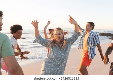 Friends enjoy a lively beach party at sunset. The group's laughter and dance moves create a vibrant outdoor atmosphere. - Powered by Shutterstock