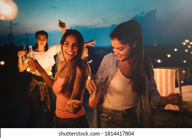 Friends Enjoying Cocktails At A Party. Group Of Happy People Having Fun, Dancing On A Rooftop