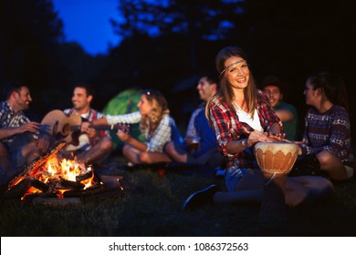 Friends enjoying music near campfire at night