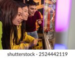 Friends Excitedly Playing Claw Machine at Arcade. Group of young friends eagerly playing a claw machine, focused and excited in a colorful arcade setting.