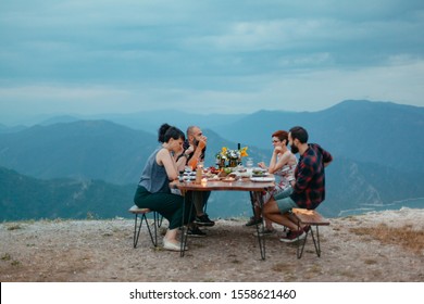 Friends and family gathered for picnic dinner for Thanksgiving. Festive young people celebrating life with red wine, grapes, cheese platter, and a selection of cold meats - Powered by Shutterstock