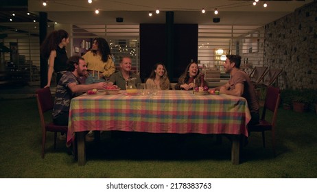 Friends And Family Gathered Together At Night In Backyard Home Laughing And Smiling