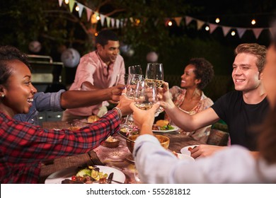 Friends and family toasting at garden dinner party, close up