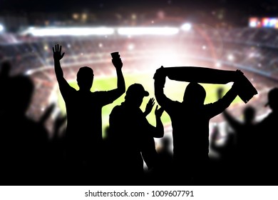 Friends At Football Game In Soccer Stadium. Crowd Cheering And Celebrating A Goal In Arena During Match. Silhouette People In Live Sport Audience Having Fun.