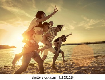 Friends Fun On The Beach Under Sunset Sunlight.