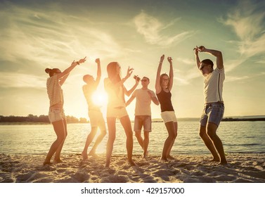 Friends funny dance on the beach under sunset sunlight. - Powered by Shutterstock