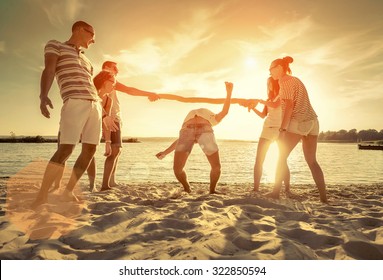 Friends funny game on the beach under sunset sunlight. - Shutterstock ID 322850594