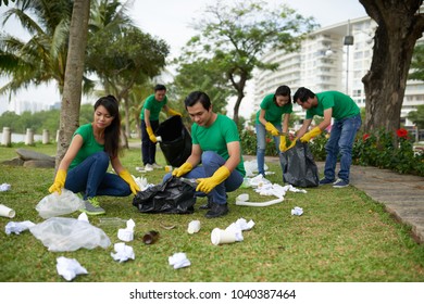 Friends in green t-shirts picking up litter in park - Powered by Shutterstock