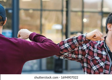 Friends Greeting With Elbows. Alternative Handshake During Coronavirus Epidemic. Covid 19. No Handshake. Coronavirus Prevention. Elbow Bumping. Greeting With Elbows Outdoors.