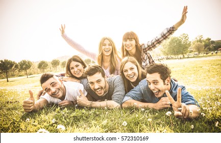 Friends group having fun together with self portrait on grass meadow - Friendship youth concept with young happy people at picnic camping outdoor - Warm vintage filter with backlight contrast sunshine - Powered by Shutterstock