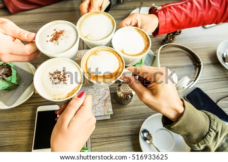 Friends group toasting cappuccino and milk with cocoa - Close up of young people drinking in coffee shop bar restaurant - Breakfast and socializing concept - Warm filter - Focus on right bottom hand