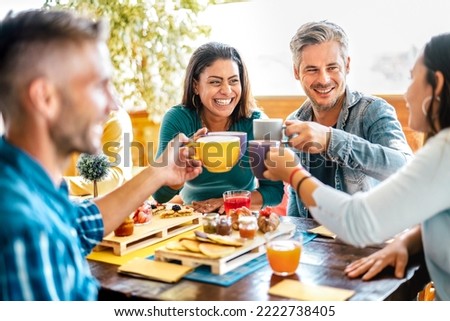 Friends group toasting cups at coffee bar rooftop - Mixed age range people talking and having fun together at cappuccino restaurant - Life style concept with happy men and women at cafe terrace