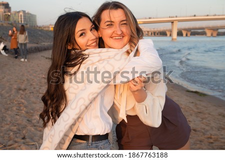 Friends have a happy time together. Young women on the beach in the evening, hugging and laughing