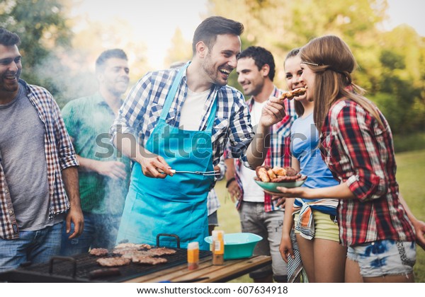Friends having a barbecue party in nature  while\
having a blast