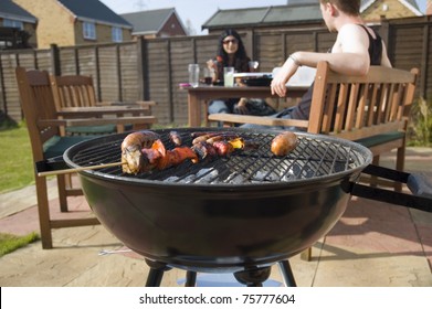 Friends Having Barbeque In Back Garden