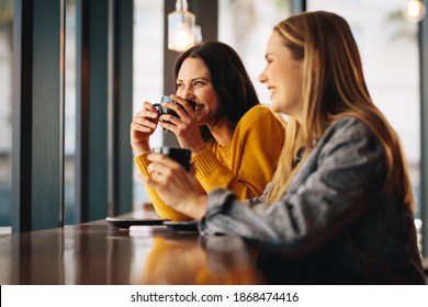 Friends having coffee and chatting in a cafe. Smiling female friends in a coffee shop. - Powered by Shutterstock