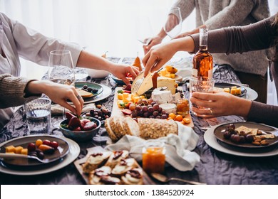 Friends Having A Dinner Party With Different Kinds Of Appetizers And Rose Wine.