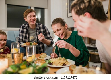 Friends Are Having A Dinner Party At Home. They Are Laughing While Eating Spaghetti Carbonara. 