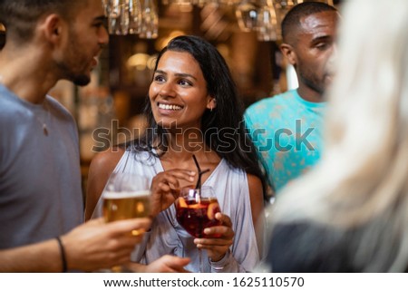 Friends having drinks together in a bar while talking. 
