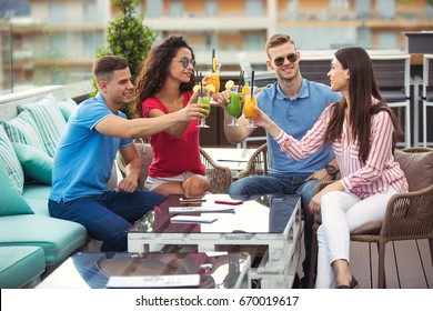 Friends having fun and drinking cocktails outdoor on a rooftop bar