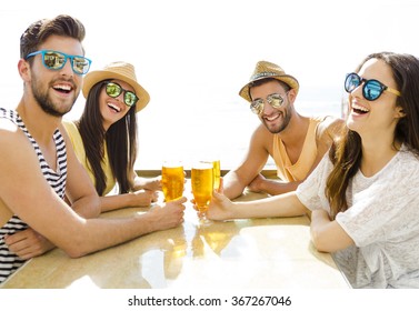 Friends Having Fun And Drinking A Cold Beer At The Beach Bar