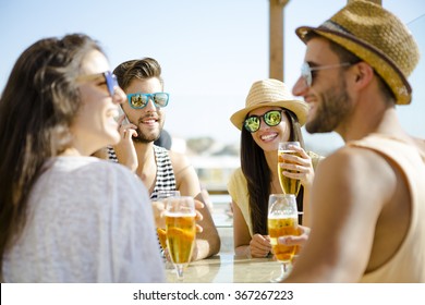 Friends having fun and drinking a cold beer at the beach bar